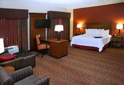 a large hotel room with a bed and a couch at Hampton Inn Waynesburg in Waynesburg
