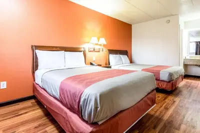 two beds in a hotel room with orange walls at Motel 6-Grove City, OH in Grove City