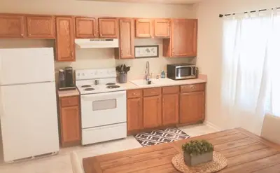 a kitchen with a white refrigerator and wooden cabinets at Landon's Attached Home in Monroe