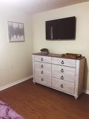 a bedroom with a dresser with a television on the wall at Landon's Attached Home in Monroe