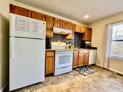 a kitchen with a white refrigerator and wooden cabinets at Jason's Attached Home in Monroe
