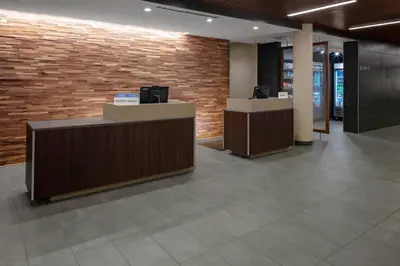 a lobby with two reception desks and a brick wall at Courtyard Cincinnati Mason in Mason
