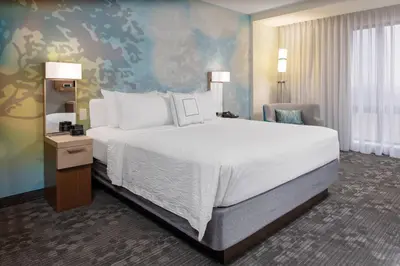 a bedroom with a large white bed and a chair at Courtyard Cincinnati Mason in Mason