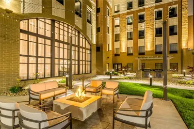 a courtyard with chairs and a table and a building at Staybridge Suites Florence - Cincinnati South by IHG in Florence