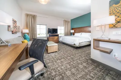 a hotel room with a bed and a desk with a chair at Staybridge Suites Florence - Cincinnati South by IHG in Florence