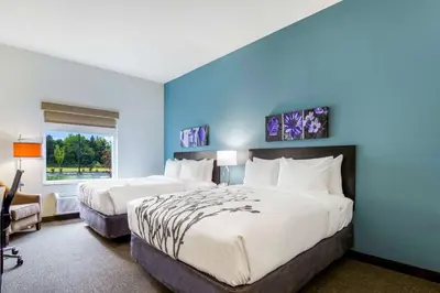 a bedroom with two beds and a blue wall at Sleep Inn Winfield - Teays Valley in Hurricane