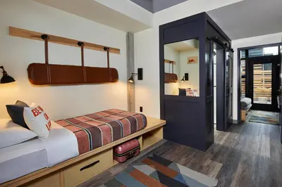 a small bedroom with a bed and a mirror at Moxy Columbus Short North in Columbus