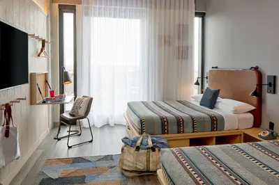 a hotel room with two beds and a desk at Moxy Columbus Short North in Columbus