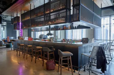 a bar with a bunch of stools in a room at Moxy Columbus Short North in Columbus