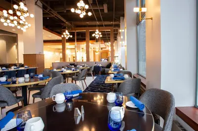 a dining room with tables and chairs and chandeliers at BLU-Tique, Akron, a Tribute Portfolio Hotel in Akron