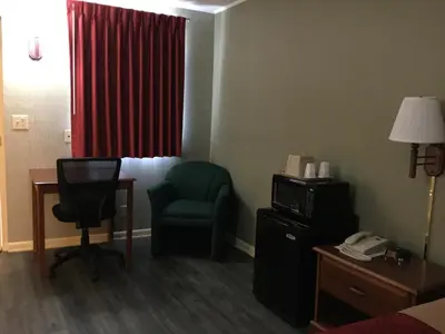 a hotel room with a chair and a desk and a chair at FALLS INN in Newton Falls