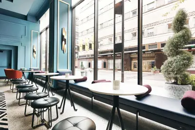 a row of tables and chairs in a room with windows at Kinley Cincinnati Downtown, a Tribute Portfolio Hotel in Cincinnati