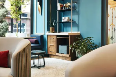 a living room with blue walls and a chair and a table at Kinley Cincinnati Downtown, a Tribute Portfolio Hotel in Cincinnati