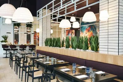 a dining room with tables and chairs and a wall with plants at Kinley Cincinnati Downtown, a Tribute Portfolio Hotel in Cincinnati