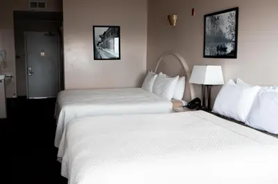 two beds in a hotel room with white sheets at West Bank Inn in Celina