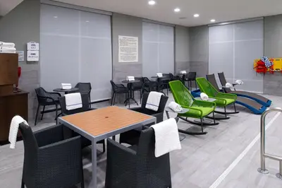 a waiting room with tables and green chairs at Hampton Inn & Suites Adrian, Mi in Adrian