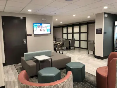 a waiting room with chairs and tables and a tv at Best Western Lexington Inn in Lexington