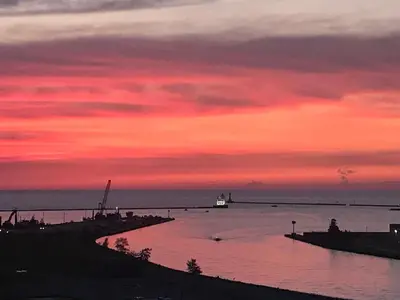 a sunset over the ocean with a boat in the water at Ariel Broadway Hotel in Lorain