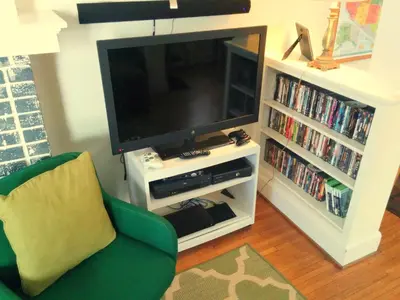 a living room with a television and a green chair at The Wayfaring Buckeye Hostel in Columbus