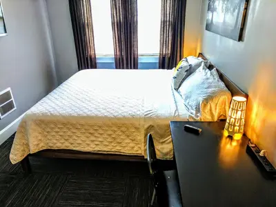 a bedroom with a bed and a table with a lamp at The Wayfaring Buckeye Hostel in Columbus
