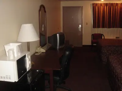a hotel room with a desk with a microwave and a television at German Village Inn Motel in Columbus