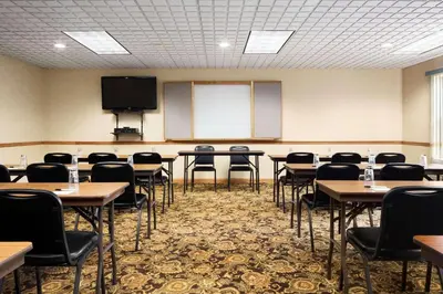a conference room with tables and chairs and a screen at Country Inn & Suites by Radisson, Columbus West, OH in Columbus