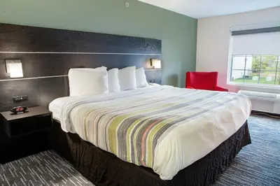 a hotel room with a large bed and a red chair at Country Inn & Suites by Radisson, Columbus West, OH in Columbus
