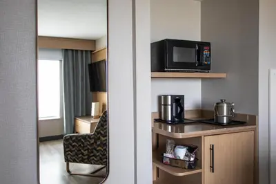 a hotel room with a microwave and a chair at Sheraton Suites Columbus Worthington in Columbus