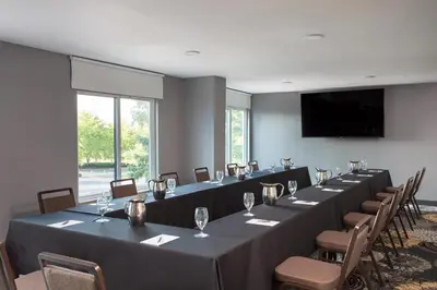 a room with long tables and chairs and a flat screen tv at Sheraton Suites Columbus Worthington in Columbus