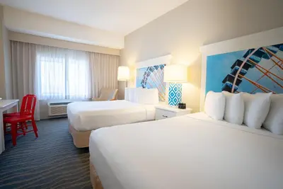 a hotel room with two beds and a desk at Cedar Point Hotel Breakers in Sandusky