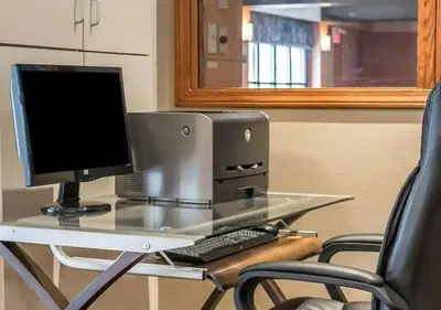 a computer on a glass desk with two chairs at Howard Johnson by Wyndham Columbus State Fairgrounds I-71 in Columbus