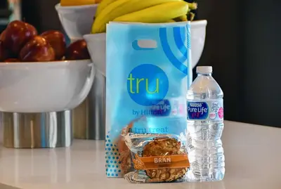 a bottle of water and a bag of food and a bowl of fruit at Tru By Hilton Monroe, MI in Monroe