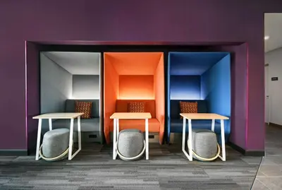 two tables and two chairs against a purple wall at Tru By Hilton Monroe, MI in Monroe