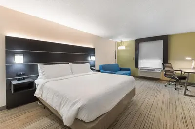 a bedroom with a large bed and a blue chair at Holiday Inn Express - Columbus Downtown by IHG in Columbus