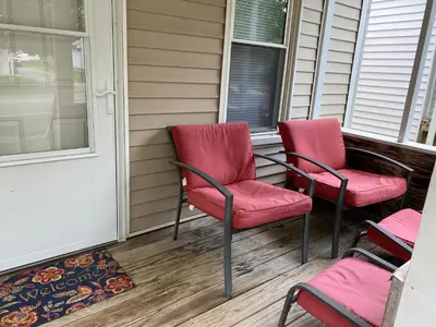 three red chairs sitting on the front porch of a house at Cozy One Bedroom House in Adrian