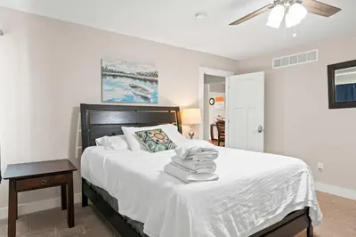 a bedroom with a bed with white sheets and a ceiling fan at Spacious 6BR Near Ark! Ample Parking, 3 Full Baths in Williamstown