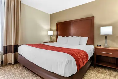 a hotel room with a large bed with a red blanket at Comfort Inn & Suites Cincinnati Eastgate in Eastgate