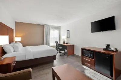 a hotel room with a bed and a desk and a tv at Comfort Inn & Suites Cincinnati Eastgate in Eastgate