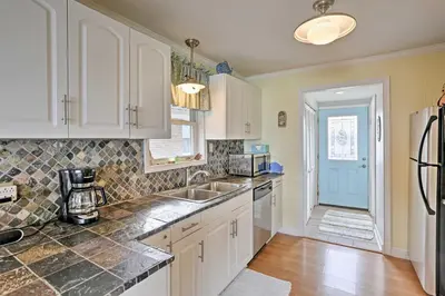 a kitchen with white cabinets and a sink and a refrigerator at Waterfront Oak Harbor Home on Lake Erie with Views! in Sand Beach