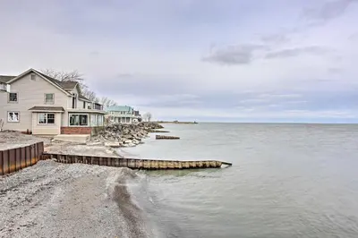 a house on the shore of a body of water at Waterfront Oak Harbor Home on Lake Erie with Views! in Sand Beach