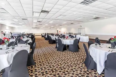 a banquet hall with white tables and black chairs at Wingate by Wyndham Marietta Conference Center Ohio in Marietta