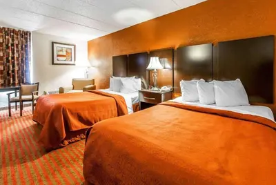 a hotel room with two beds with orange sheets at Wingate by Wyndham Marietta Conference Center Ohio in Marietta