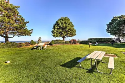 a park with three picnic tables in the grass at Waterfront Port Clinton Condo with Pool Access! in Port Clinton