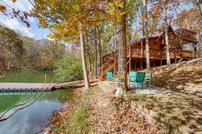 a log cabin in the woods next to a lake at Hocking Hills Lake Gem with Hot Tub, Dock, 100 Acres in Hamden