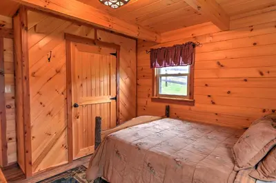 a bedroom with a bed in a log cabin at Rustic Dundee Log Cabin with Hot Tub and Forest Views! in Dundee