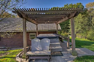 two chairs sitting under a wooden pergola at Rustic Dundee Log Cabin with Hot Tub and Forest Views! in Dundee