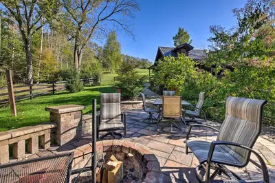 a patio with chairs and a fire pit at Rustic Dundee Log Cabin with Hot Tub and Forest Views! in Dundee