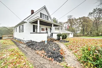 a white house with autumn leaves on the ground at Burgettstown Home - 7 Mi to KeyBank Pavilion in Burgettstown