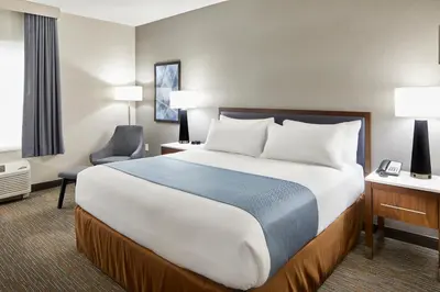a hotel room with a large bed and a chair at Wingate by Wyndham Hurricane WV in Hurricane
