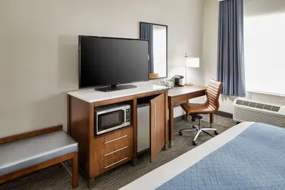 a hotel room with a television and a desk with a chair at Wingate by Wyndham Hurricane WV in Hurricane